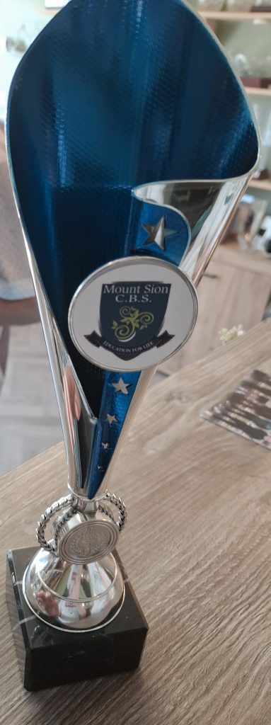 A trophy with a sticker of a school crest reading "Mount Sion C.B.S, Education for Life" 
